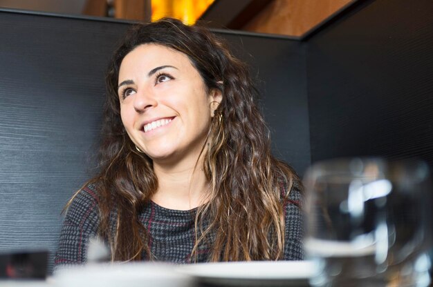 Photo gorgeous smiling girl with curly brown hair sitting at restaurant