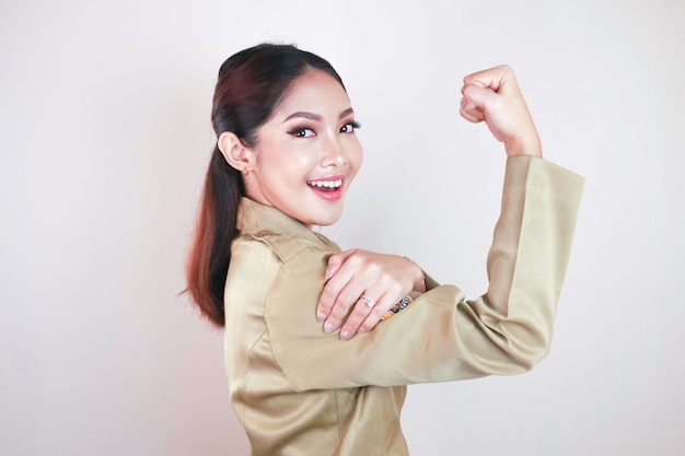 Gorgeous strong young Asian woman wearing a brown uniform and showing biceps and smiling Indonesian girl strong concept