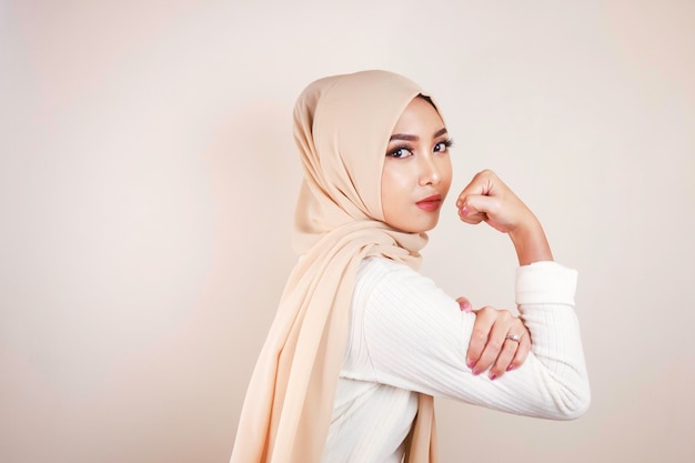 Gorgeous strong young Muslim woman isolated over white background wall showing biceps