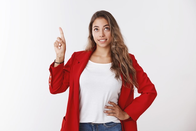 Splendida ed elegante donna d'affari moderna di successo con una giacca rossa alla moda che punta il dito verso l'alto