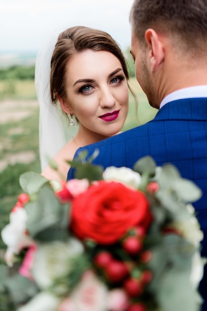 豪華なスタイリッシュな結婚式のカップルは、緑の芝生に立って