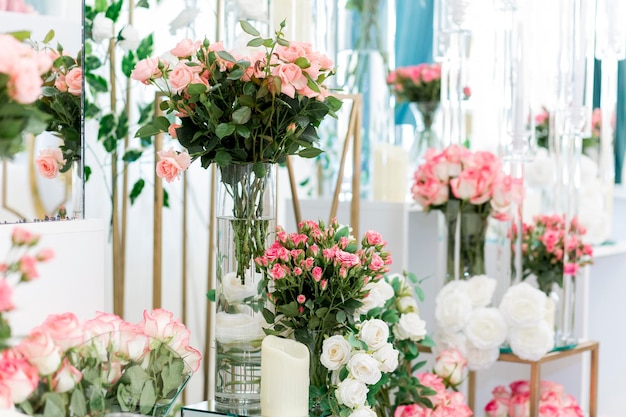 Gorgeous wedding decoration in restaurant with natural roses in glasses filled with water and designed with candles