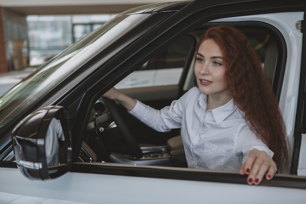 Donna splendida che compra nuova automobile al concessionario