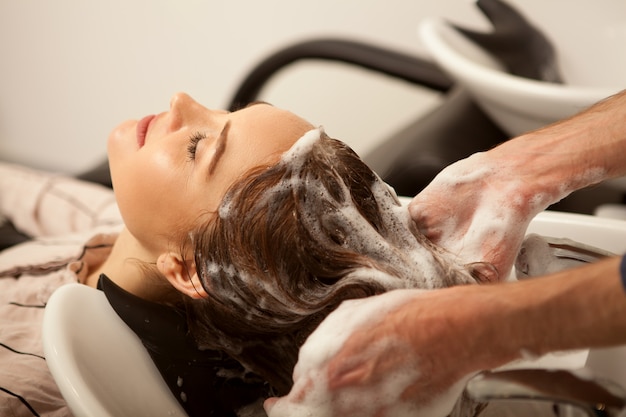 Foto donna splendida che fa lavare i suoi capelli dal parrucchiere