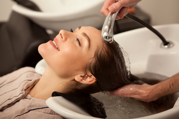 Gorgeous woman having her hair washed by hairdresser