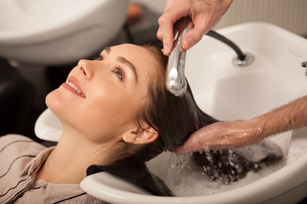 Foto donna splendida che fa lavare i suoi capelli dal parrucchiere