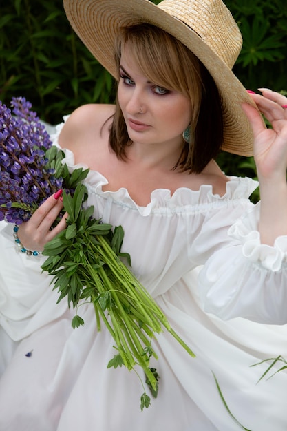Великолепная женщина в длинном легком летнем платье и шляпе на цветочном поле