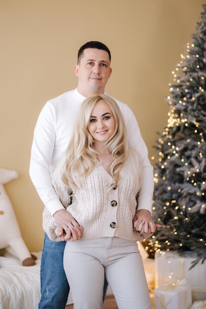 Gorgeous woman with her husband posing to photographer at home Christmas mood