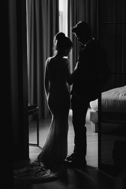 Gorgeous woman with red lips and big eyes stands with man in hotel room