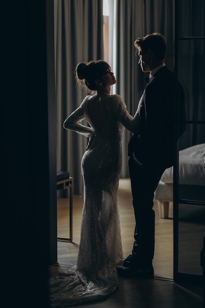 Gorgeous woman with red lips and big eyes stands with man in hotel room