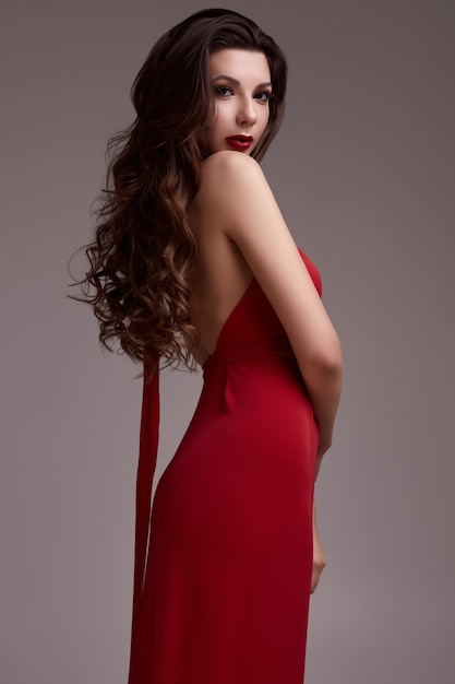 빨간 드레스에 곱슬 머리를 가진 화려한 젊은 갈색 머리 여자