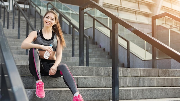 スタジアムの階段でリラックスして座っているゴージャスな若いフィットの女性