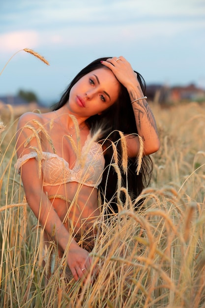 Foto splendida giovane donna nel campo in mutande sotto i raggi del sole della sera