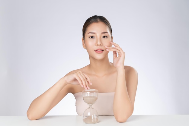 Gorgeous young woman holding an hourglass demonstrated anti aging concept