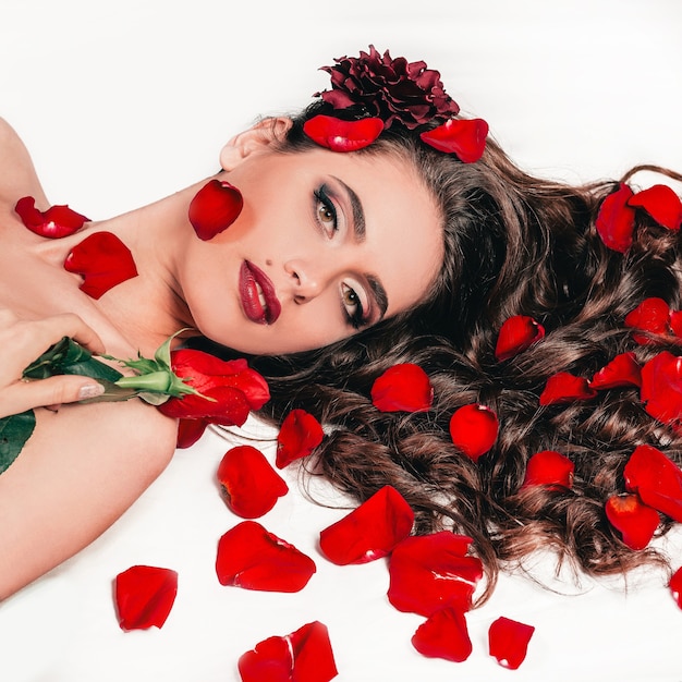 Gorgeous young woman lying among rose petals. lifestyle and body care