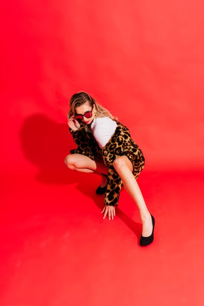 Gorgeous young woman posing in luxurious fur coat and bodysuit Fashion beauty Studio shot