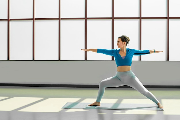 Gorgeous young woman practicing yoga exercising indoors in light and spacious yoga studio Calmness and relax female happiness