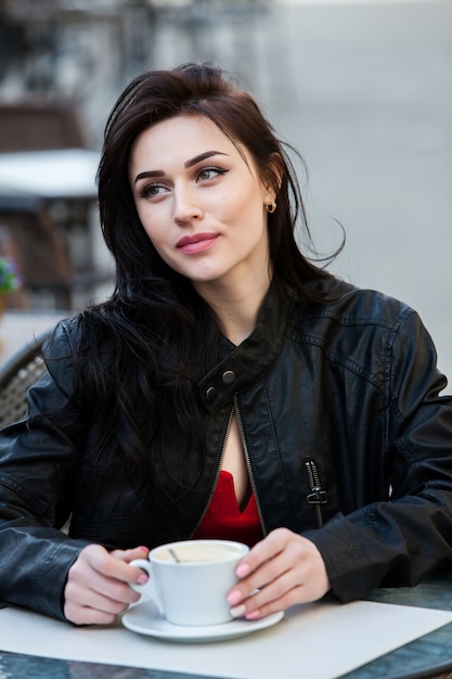 Gorgeous young woman with cup of coffee in city street