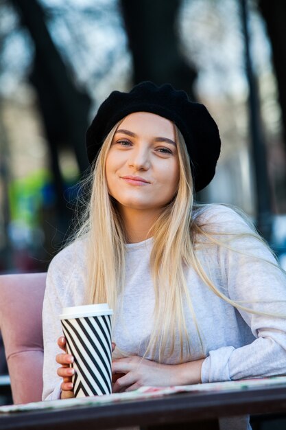 Gorgeous young woman with cup of coffee in city street