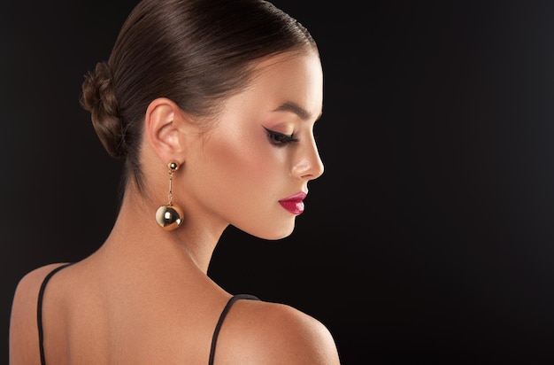 Photo gorgeous young woman with splendid professional makeup gilded earrings with big balls in her ears