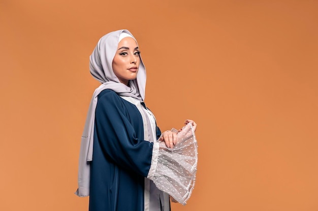 스튜디오에서 포즈를 취하는 카메라를 보고 있는 Gorgeus 이슬람 여성. 그녀는 심각합니다.