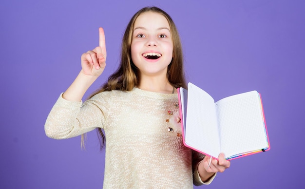 Got great idea happy little girl holding open idea book and keeping finger raised smiling small child having an idea idea came into her head copy space