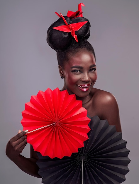 Got to have tons of red in my life Studio portrait of a beautiful young woman wearing Asian inspired makeup and posing with origami against a grey background