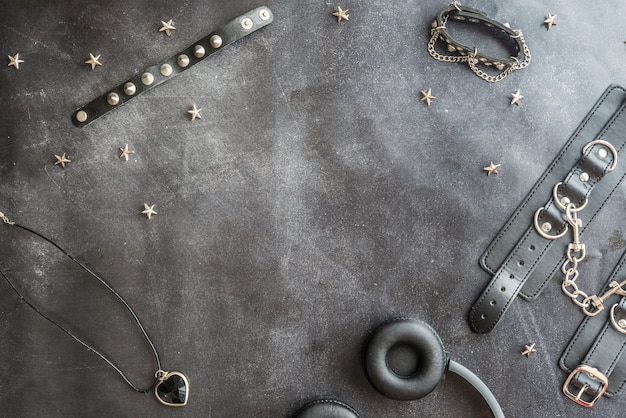 Gothic accessories and headphones on black background