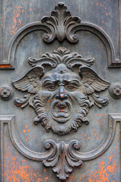 Gothic mask on an old wodden door in Milan - Italy