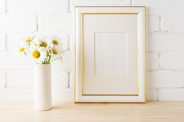 Goud versierd frame mockup met daisy in de buurt van geschilderde bakstenen muur