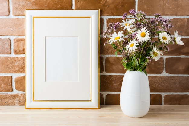 Goud versierd frame mockup met wilde bloemen boeket blootgesteld bakstenen muur