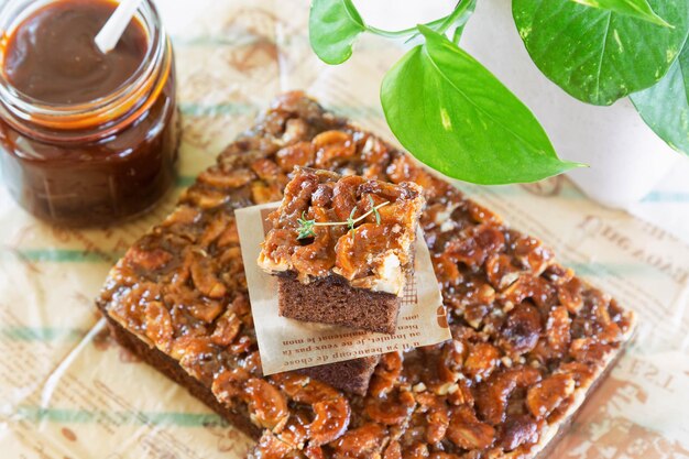 Foto goudbruin vierkant van plakje toffeecake topping cashewnoot en karamelsaus