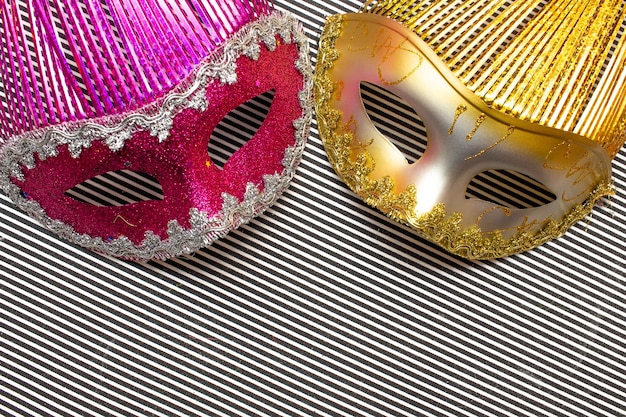 Gouden advertentie roze carnaval maskers op een zwart-wit gestreepte achtergrond en kleurrijke bloemen