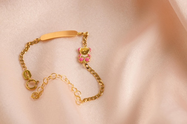 Gouden armband met roze emaille beertje op een roze achtergrond Kinderversiering Reclamestilleven