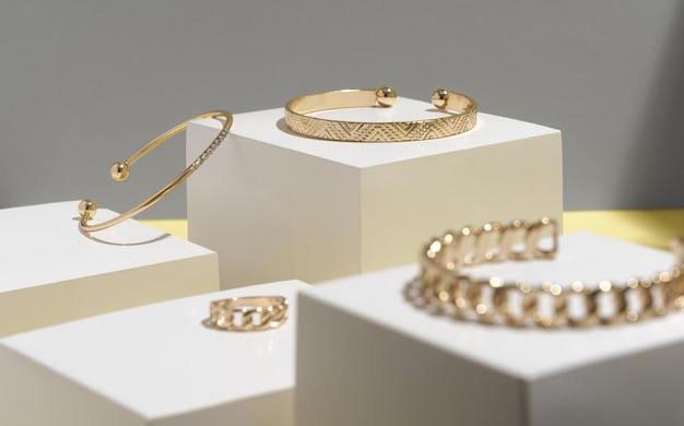 Gouden armbanden en ring op witte kubieke blokken met exemplaarruimte