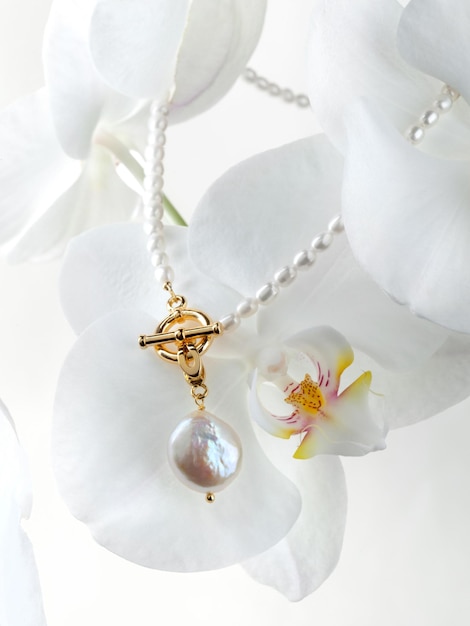 Gouden barokke parelhanger en ketting op witte orchideebloem