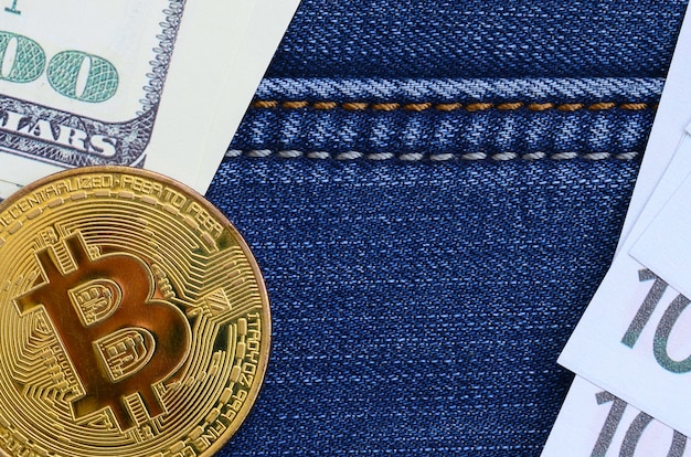 Gouden Bitcoin, dollar en euro rekeningen ligt op een jeans stof