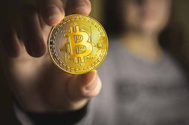 Gouden bitcoin in de hand van een jonge vrouw, vergrote weergave van cryptovaluta, zaken, online virtuele toekomstige valutaconceptfoto