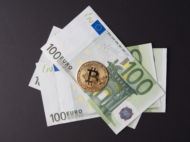 Gouden bitcoin is in biljetten van 100 euro. het concept van cryptocurrency en geld. Bovenaanzicht, zwarte achtergrond