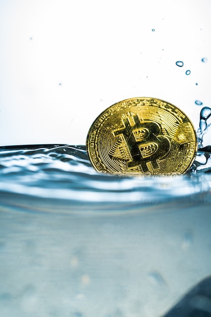 Gouden bitcoin met waterplons op witte achtergrond.