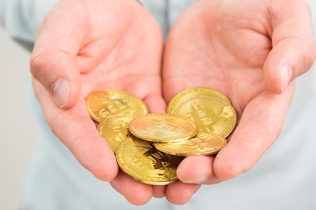 Gouden bitcoin munten in mans hand crypto valuta betalingsconcept