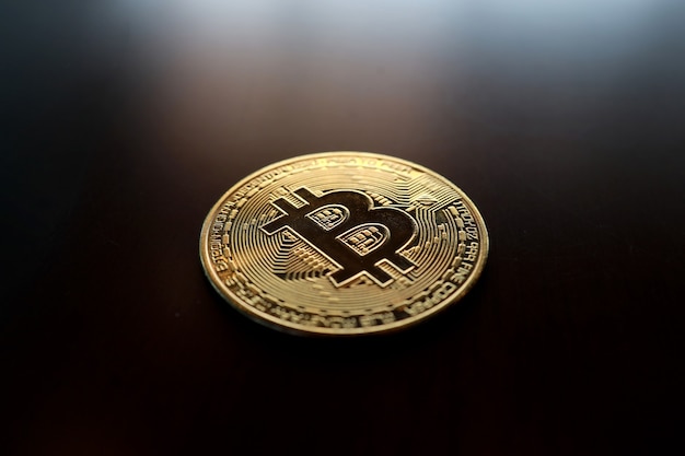 Gouden bitcoin op tafel met soft focus en achtergrondverlichting. cryptocurrency-concept