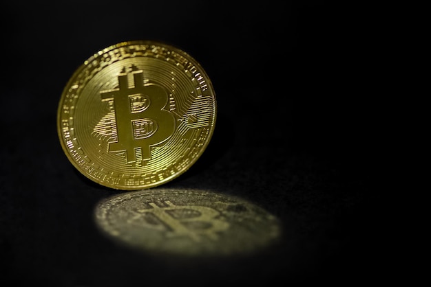 Gouden bitcoin reflecteert in licht op een donker oppervlak