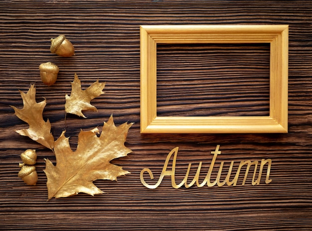 Gouden bladeren eiken en een frame op een bruine oude tafel old