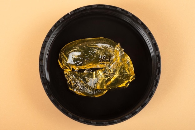 Gouden cannabis wax in een glazen pot met hoge thc schar in glazen fles