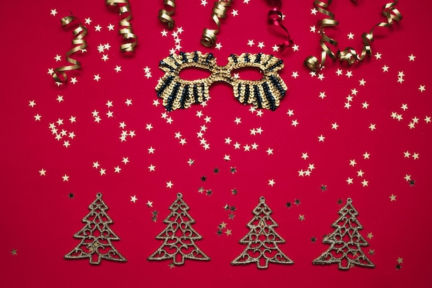Gouden carnaval masker en kerst ornamenten met gouden sterren op rode achtergrond bovenaanzicht kopie ruimte