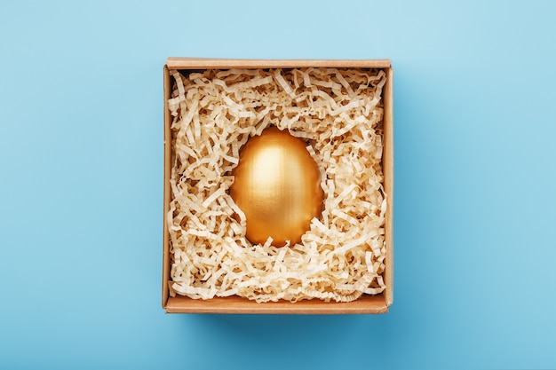 Gouden ei in een doos op een blauwe achtergrond concept van exclusiviteit, beste keuze, prijs, speciale verrassing, duur geschenk.
