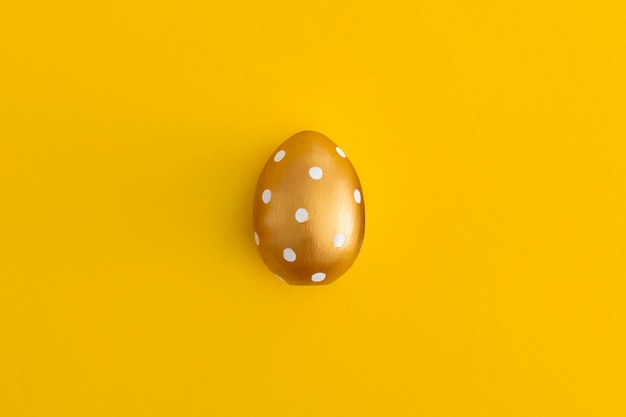 Gouden ei op een gele achtergrond Minimaal Pasen concept