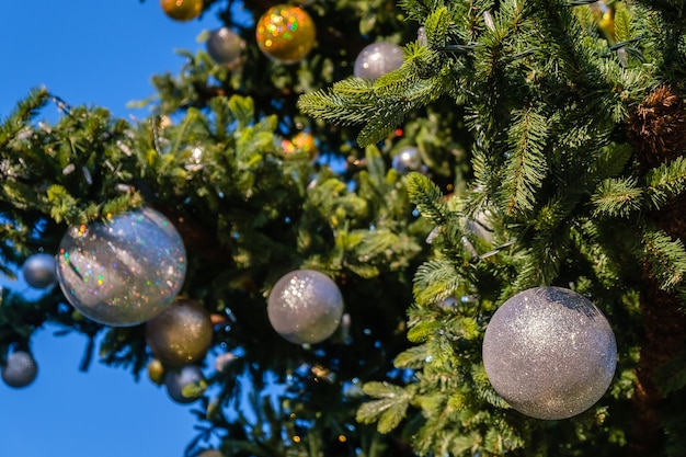 Gouden en witte nieuwjaarsversieringen en slinger op de kerstboom buitenshuis