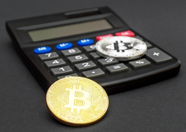 Gouden en zilveren bitcoin-munten met rekenmachine op zwarte achtergrond bedrijfsconcept